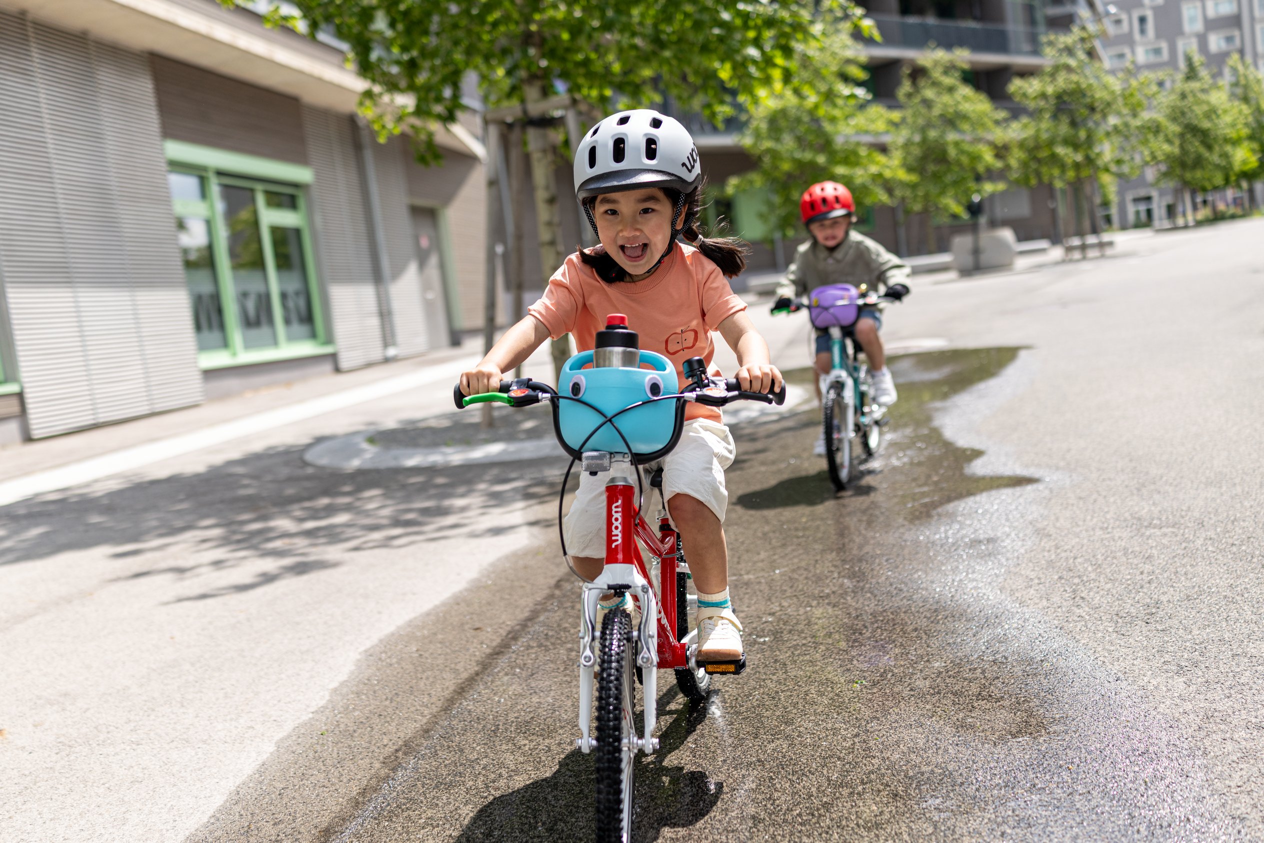 Child riding a green woom GO has the POP Kids' Bike Basket on their handlebars decorated with fun POP ONS Bike Charms