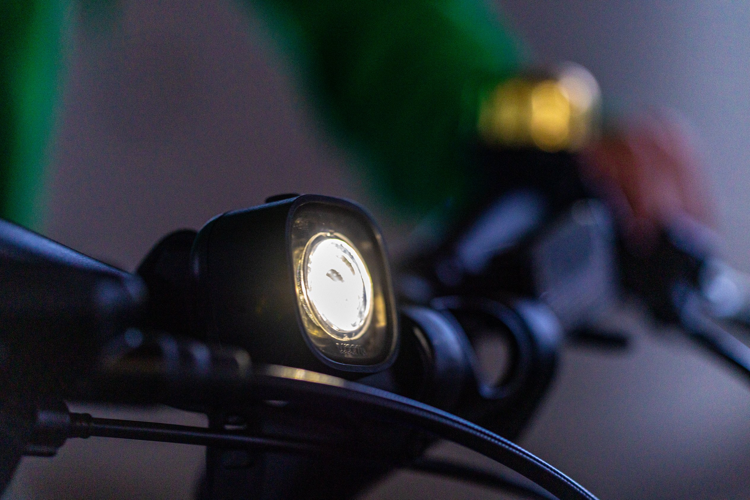 Weißes BEAM Frontlicht von woom strahlt am schwarzen Lenker eines Kinderrades von woom.