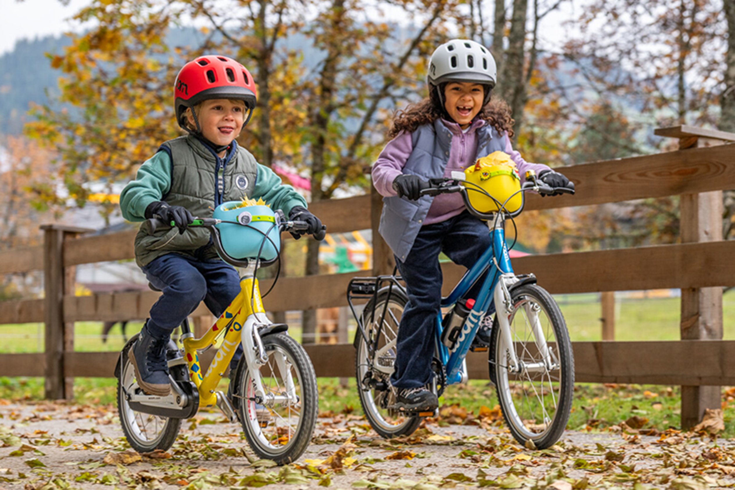A child riding a green woom GO with the POP Kids' Bike Basket on their handlebars decorated with fun POP ONS Bike Charms