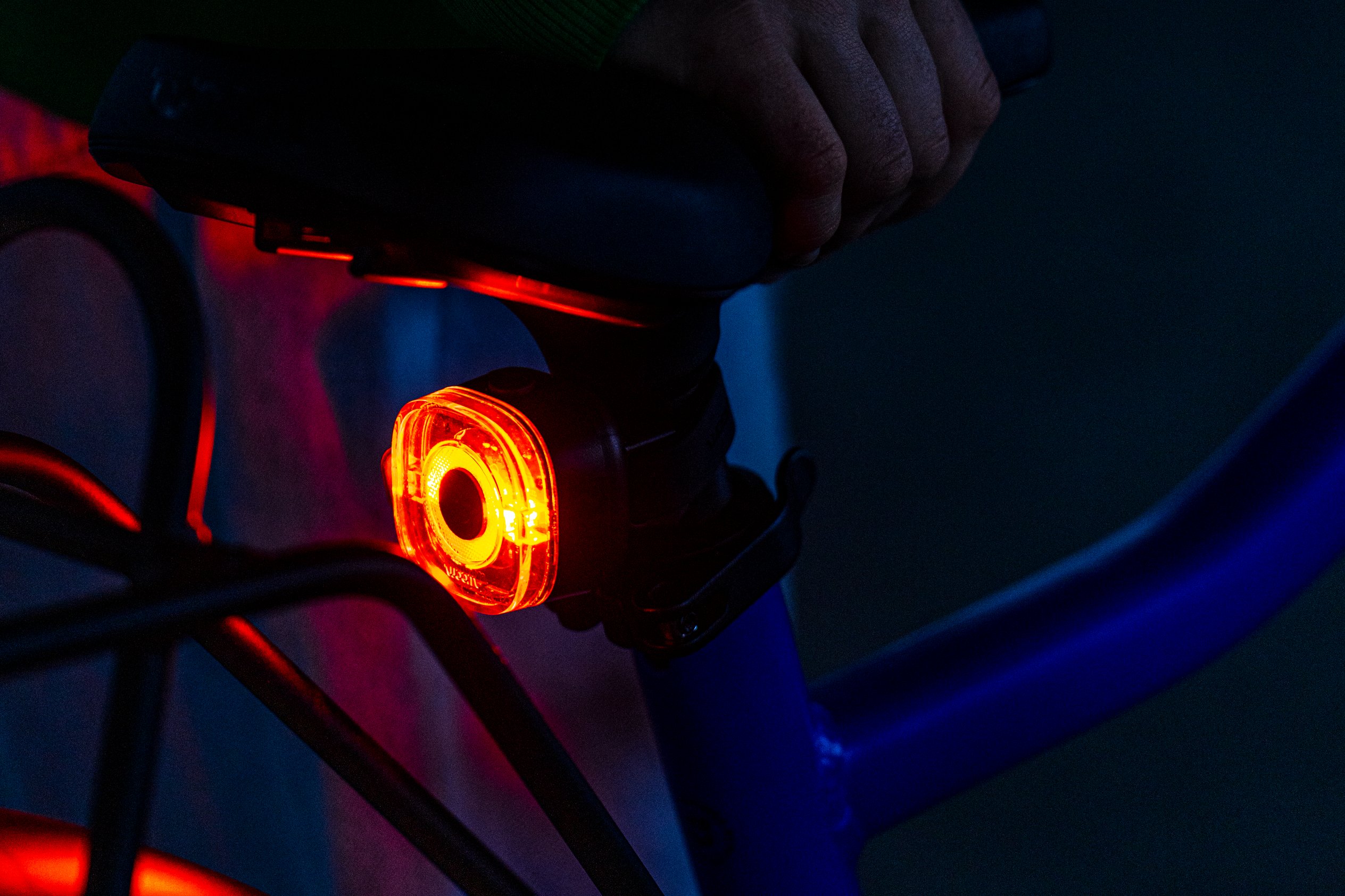 woom BEAM rear red safety light mounted under kids bike saddle for nighttime visibility.